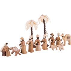 a group of wooden figurines with palm trees and people dressed in traditional clothing