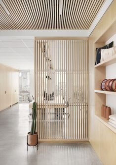 an empty room with shelves and plants on the wall, along with wooden slatted partitions