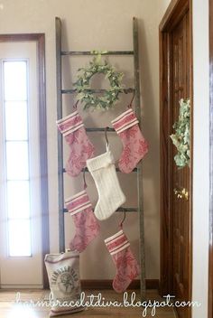 an old ladder used as a christmas stocking holder for stockings and potted plants