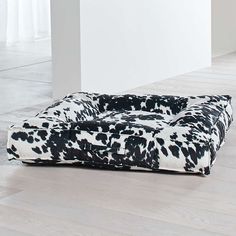 a black and white cow print dog bed sitting on the floor in an empty room