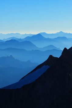 the view from the top of a mountain looking down at some mountains and blue sky