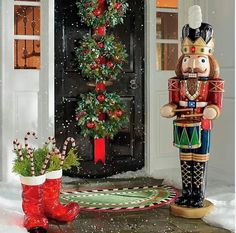 a nutcracker and christmas tree in front of a door with snow on the ground