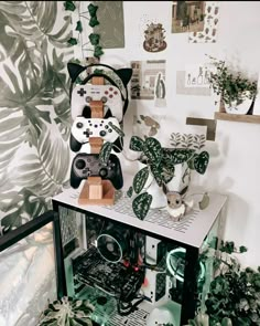 a room with plants and video game controllers on top of the shelf in front of it