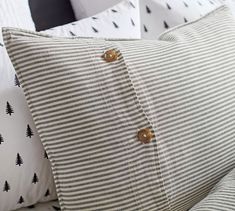 a close up of a pillow on a bed with black and white striped linens