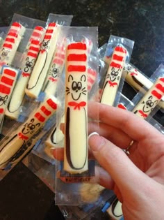 a person holding some kind of cat in the hat shaped cookies with candy sticks sticking out of them