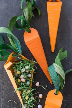 carrots and other vegetables made out of paper on a black surface with green leaves