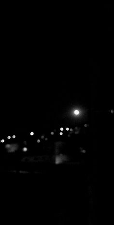 black and white photograph of street lights in the dark night time with blurry background