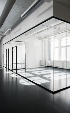 an empty room with glass partitions and doors on the wall to let light in