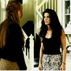 a woman standing in front of a mirror looking at another woman with long hair on her head