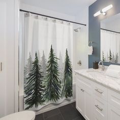 a bathroom with a shower curtain that has trees on it