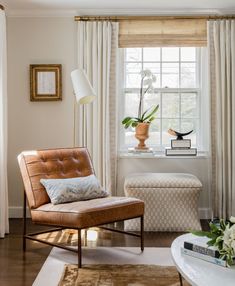 a living room filled with furniture and a window covered in white drapes next to a table