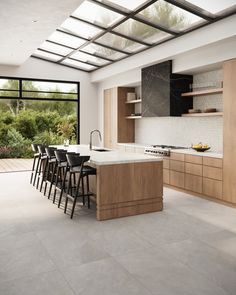 a modern kitchen with an island counter and bar stools in the center, surrounded by wooden cabinets