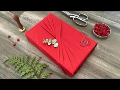 a red box sitting on top of a wooden floor next to scissors and raspberries