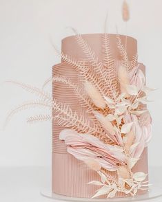 a pink cake with white flowers and leaves on it