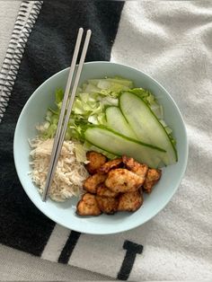 a bowl filled with meat and vegetables next to chopsticks on top of a towel