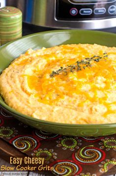 an easy cheesy slow cooker grits in a green bowl on a table