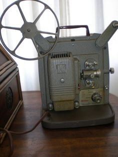 an old movie projector sitting on top of a wooden table next to a window