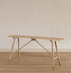 a wooden table sitting on top of a hard wood floor next to a white wall