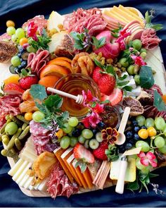 a platter filled with assorted fruits and meats on top of a blue cloth