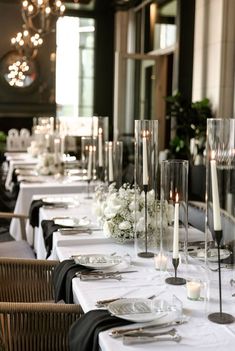 a long table is set with white flowers and candles for an elegant dinner or party