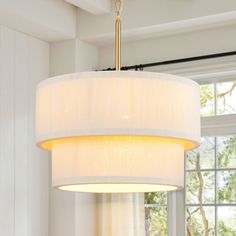 a chandelier hanging from the ceiling in a living room with white walls and windows