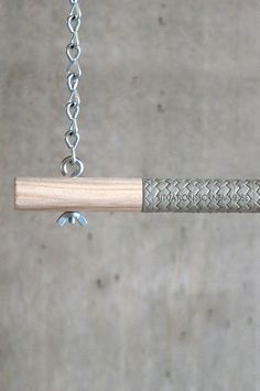 a close up of a metal object on a chain with a wooden stick attached to it