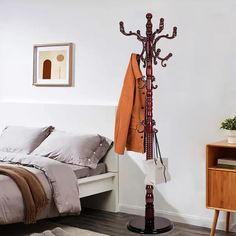 a coat rack in the corner of a bedroom next to a bed with pillows and blankets