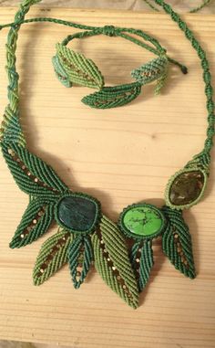 a green beaded necklace and earring set on a wooden surface with beads around it