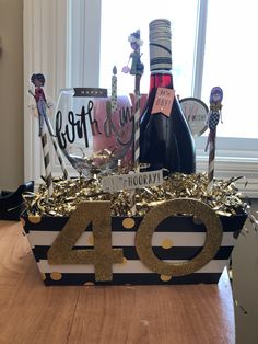 a table topped with a bottle of wine next to a sign that says forty and candles