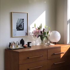 a wooden dresser topped with lots of bottles and flowers