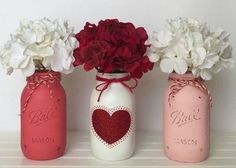 three mason jars with flowers and hearts painted on them are lined up against a white wall