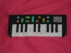 a black and white piano made out of legos on a pink surface with the keys missing