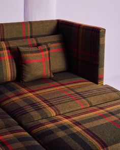 a plaid couch with two pillows on it's back and the seat folded down