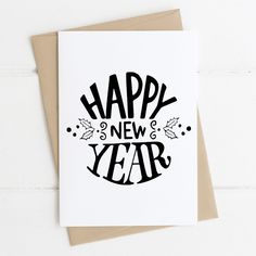 a card with the words happy new year written in black ink on white paper next to a brown envelope