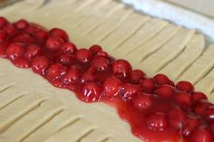 a pastry with red fruit on top of it in the shape of a long line