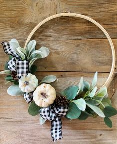 a wreath decorated with white pumpkins and greenery on top of a wooden table