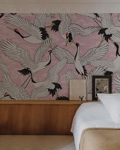 a bedroom with pink wallpaper and cranes on the wall