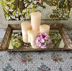 four lit candles on a tray with flowers