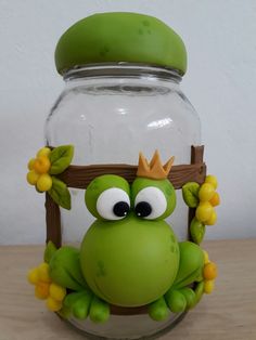 a frog with a crown sitting in front of a jar