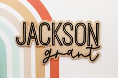 a wooden sign that says jackson grant on the side of a wall with rainbows in the background