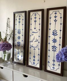 three framed art pieces on a wall with flowers in vases next to each other