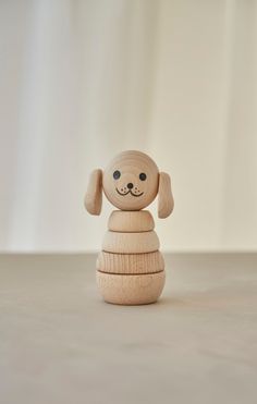 a wooden toy dog sitting on top of a stack of stacked wood discs with eyes closed