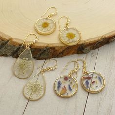 three dandelions are hanging from earrings on a piece of wood