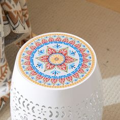 a white table with a colorful design on it and a chair in the back ground