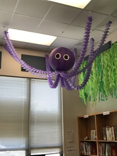 a purple spider hanging from the ceiling in an office