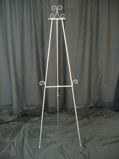 a white metal easel stands against a gray backdrop