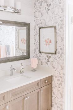 a bathroom with two sinks and a mirror on the wall next to it is decorated with flowers