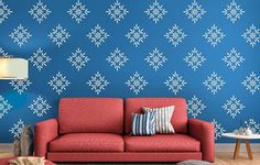 a red couch sitting in front of a blue wall with snowflakes on it