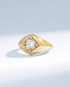 a yellow gold ring with a square diamond in the center, on a white background