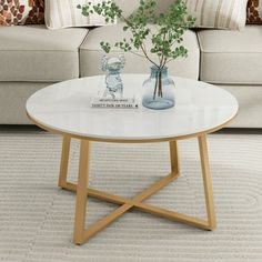 a living room with a couch, coffee table and two vases filled with flowers